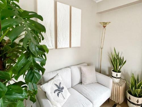 a white couch in a living room with plants at L'Artistik - Appartement 5 min à pied du port et parking privé in Vannes