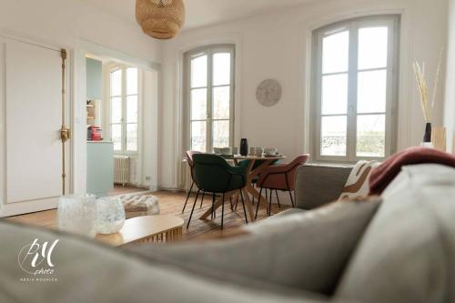 ein Wohnzimmer mit einem Sofa und einem Tisch mit Stühlen in der Unterkunft Les pierres blanches : T2 - Hypercentre Angoulême in Angoulême