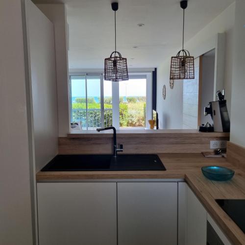 une cuisine avec un évier et une fenêtre dans l'établissement Coté Mer, au Cap d'Agde