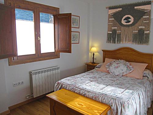 a small bedroom with a bed and a window at Les LLaus in Ribera de Cardós