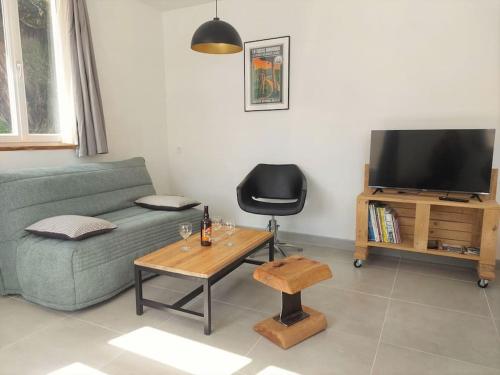 sala de estar con sofá, mesa y TV en L'aigrette moderne, ensoleillé et bien placé, en Thury-Harcourt