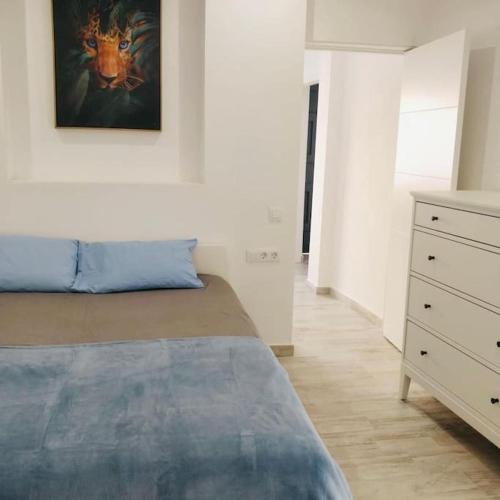 a bedroom with a bed and a dresser with a painting on the wall at "Casa Jasmin" 14 Calle Medina Quesada in Tazacorte