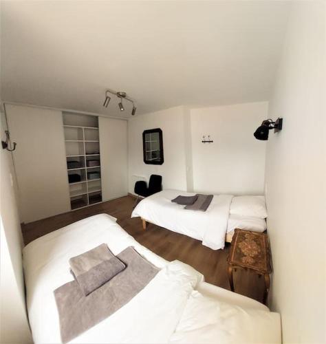 Cette chambre blanche comprend deux lits et une table. dans l'établissement L'aigrette moderne, ensoleillé et bien placé, à Thury-Harcourt