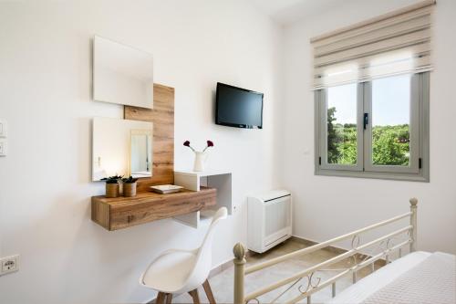 a white room with a chair and a tv on a wall at Alkmini Apartment in Loutra