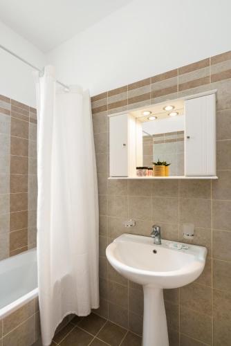 a bathroom with a sink and a white shower curtain at Alkmini Apartment in Loutra