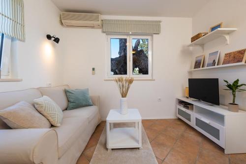 a living room with a white couch and a tv at Apartment Judita in Dubrovnik