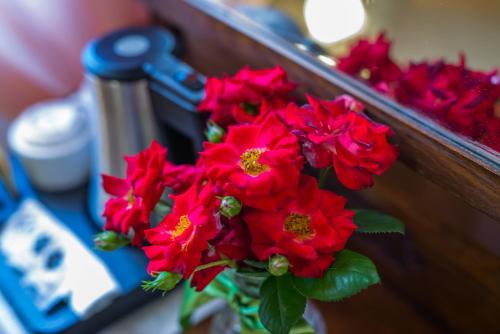 a bouquet of red flowers in front of a mirror at Hotel & SPA L'Antico Forziere in Deruta