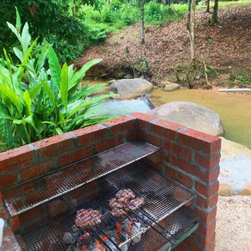 a brick fire pit with a grill next to a stream at Tingkat Valley in Ipoh