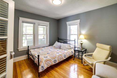 a bedroom with a bed and a chair and two windows at Cozy Indiana Getaway Near Washington Park Zoo! in Michigan City