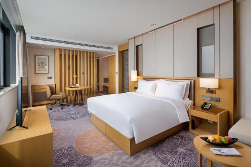 a bedroom with a large white bed and a living room at Holiday Inn Tianjin Xiqing by IHG in Tianjin