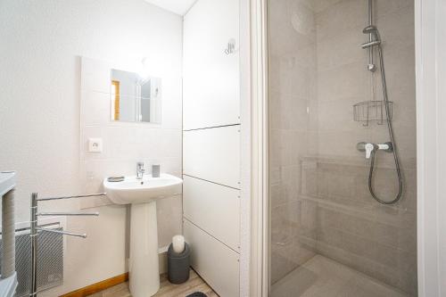 ein weißes Bad mit einem Waschbecken und einer Dusche in der Unterkunft Chalet récent cœur station in Thollon