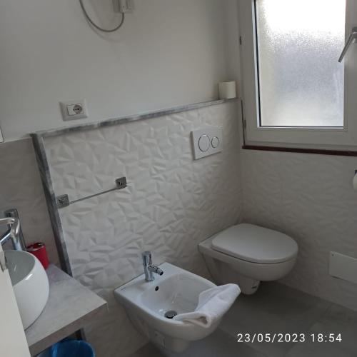 a white bathroom with a toilet and a sink at Marina D'Agrò Residence in Santa Teresa di Riva
