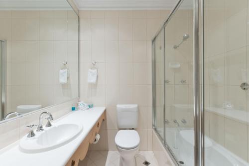 a bathroom with a toilet and a sink and a shower at European Hotel in Perth