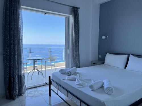 a bedroom with a bed and a balcony with a table at Palasa View in Dhërmi