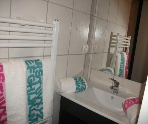 a bathroom with a sink and a mirror and towels at Gîtes de Charme Chez Christine in Ottrott