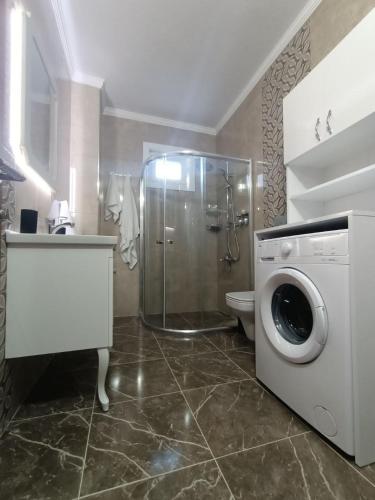 a bathroom with a shower and a washing machine at Clove Boutique House Apart in Akcaabat