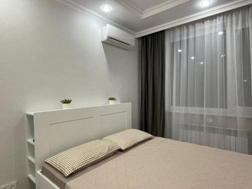 Un dormitorio blanco con una cama y una ventana. en Nova Center, en Astana