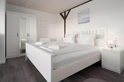 Emmelsbüll-HorsbüllにあるFerienhaus Hemenswarft direkt an der Nordsee mit Meerblickの白いベッドルーム(白い枕の大きな白いベッド付)