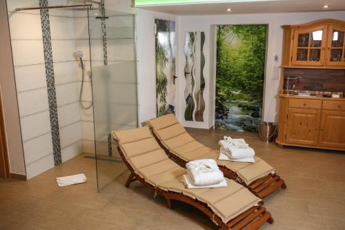 two lounge chairs and a shower in a room at Black&White Luxus Appartement - Wilbergé Chalets in Gotteszell