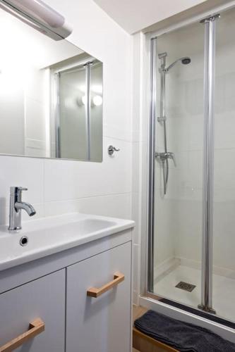 La salle de bains blanche est pourvue d'une douche et d'un lavabo. dans l'établissement Le Petit Tyard, à Chalon-sur-Saône
