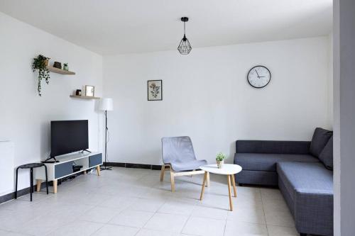 - un salon avec un canapé, une table et une télévision dans l'établissement Le Petit Tyard, à Chalon-sur-Saône