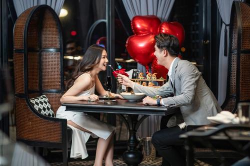 a man and woman sitting at a table with balloons at La Sinfonía Majesty Hotel and Spa in Hanoi