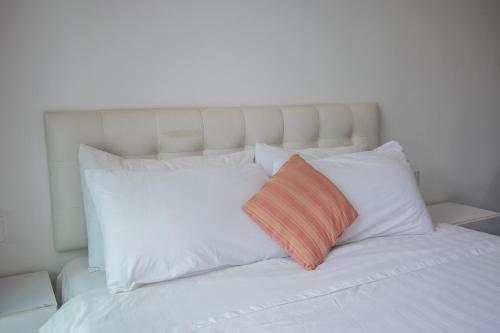 a white bed with white pillows and an orange pillow at MyRehat Suites Bukit Ceylon in Kuala Lumpur
