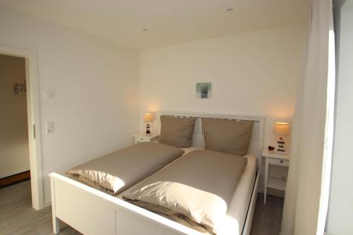 1 dormitorio blanco con 1 cama con 2 almohadas en Mein-Ostseeplätzchen Haus am Meer 9, en Niesgrau