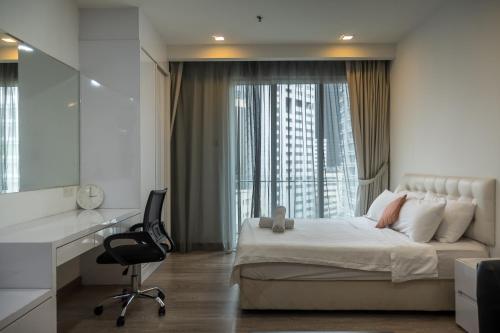 a bedroom with a bed and a desk and a window at MyRehat Suites Bukit Ceylon in Kuala Lumpur