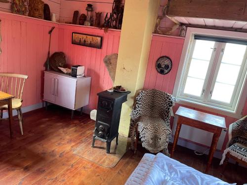 a living room with pink walls and a wood stove at Kræmmervika Rorbuer - Rustic Cabins & Hostel in Lofoten in Ballstad