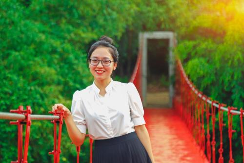 a woman is standing on a red bridge at MEDDOM Park in Cao Phong