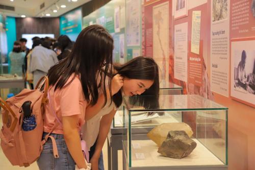a woman looking at a rock in a glass case at MEDDOM Park in Cao Phong