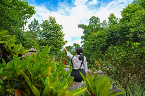 a woman sitting on a rock in a garden at MEDDOM Park in Cao Phong