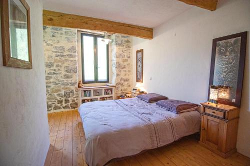 une chambre avec un lit et un mur en pierre dans l'établissement Le Foulon en Baronnies, à Buis-les-Baronnies