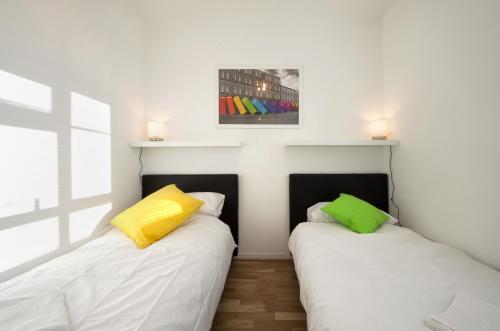 two beds in a room with white and yellow pillows at Central London 2 Bedroom Apartment in London