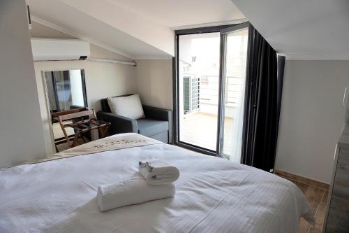 a white bed in a room with a large window at ReynaBe Boutique Hotel in Dikili