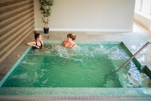 two women in a jacuzzi in a swimming pool at Bacolux Diana, Herculane in Băile Herculane