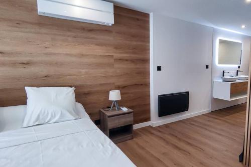 une chambre avec un lit blanc et un mur en bois dans l'établissement T3 cosy et climatisé avec vue montagne, à Moustajon
