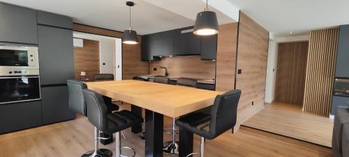 une cuisine avec une table en bois et des armoires noires dans l'établissement T3 cosy et climatisé avec vue montagne, à Moustajon
