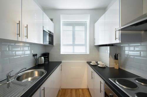 ロンドンにあるCentral London 2 Bedroom Apartmentの白いキャビネット、シンク、窓付きのキッチン