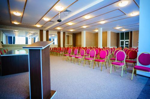 a conference room with pink chairs and a podium at Bacolux Diana, Herculane in Băile Herculane