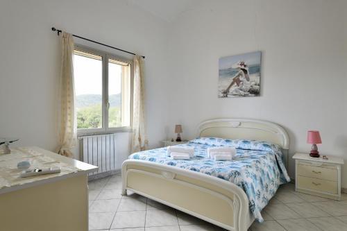 Habitación blanca con cama y ventana en casa vacanza Luciano, en Tortolì