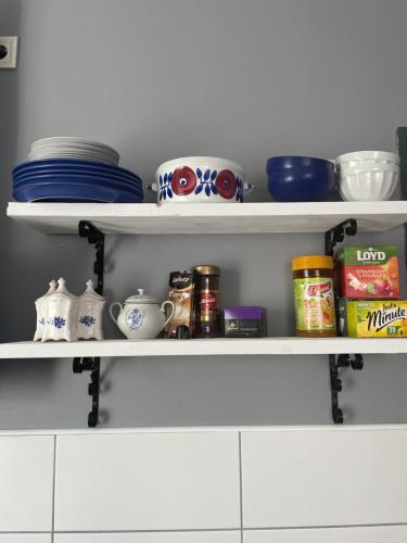 a kitchen shelf with dishes and other items on it at Skrunda Apartments Elvira in Skrunda