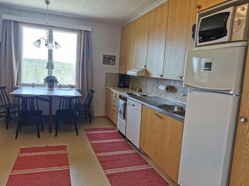 eine Küche mit einem weißen Kühlschrank und einem Tisch mit einem Fenster in der Unterkunft Ulvovan Suden Majatalo 