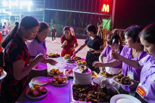a group of people standing around a table with food at MEDDOM Park in Cao Phong