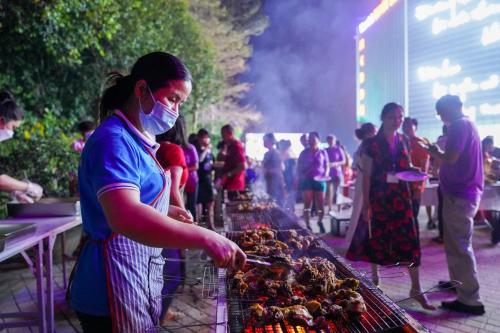 a woman in a face mask cooking food on a grill at MEDDOM Park in Cao Phong