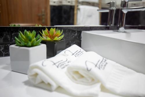 een badkamer met witte handdoeken, een wastafel en planten bij Lino's Family Guesthouse in Peso da Régua