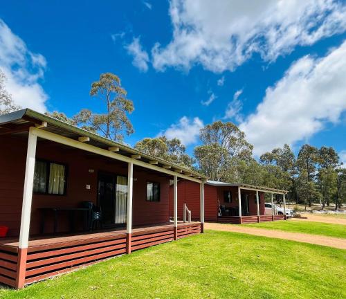 una casa rossa con un prato verde davanti di BIG4 Taunton Farm a Cowaramup