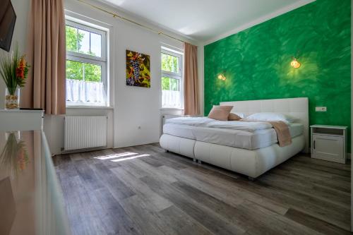 a bedroom with a white bed and a green wall at Albizia-Apartments in Baden