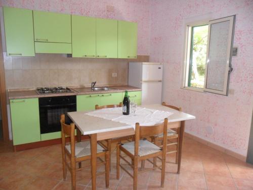 una cocina con armarios verdes y una mesa con una botella de vino en agriturismo heaven trilocale 3, en Ricadi